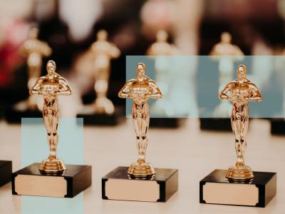 Tre prisstatuetter i forgrunden med flere lignende statuetter bagved.